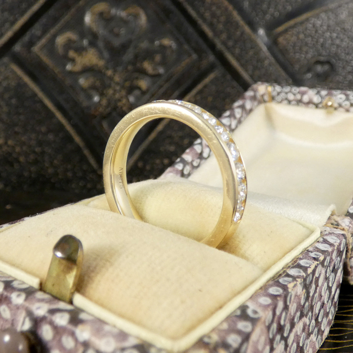 Gold ring with diamonds in a jewelry box on a textured surface