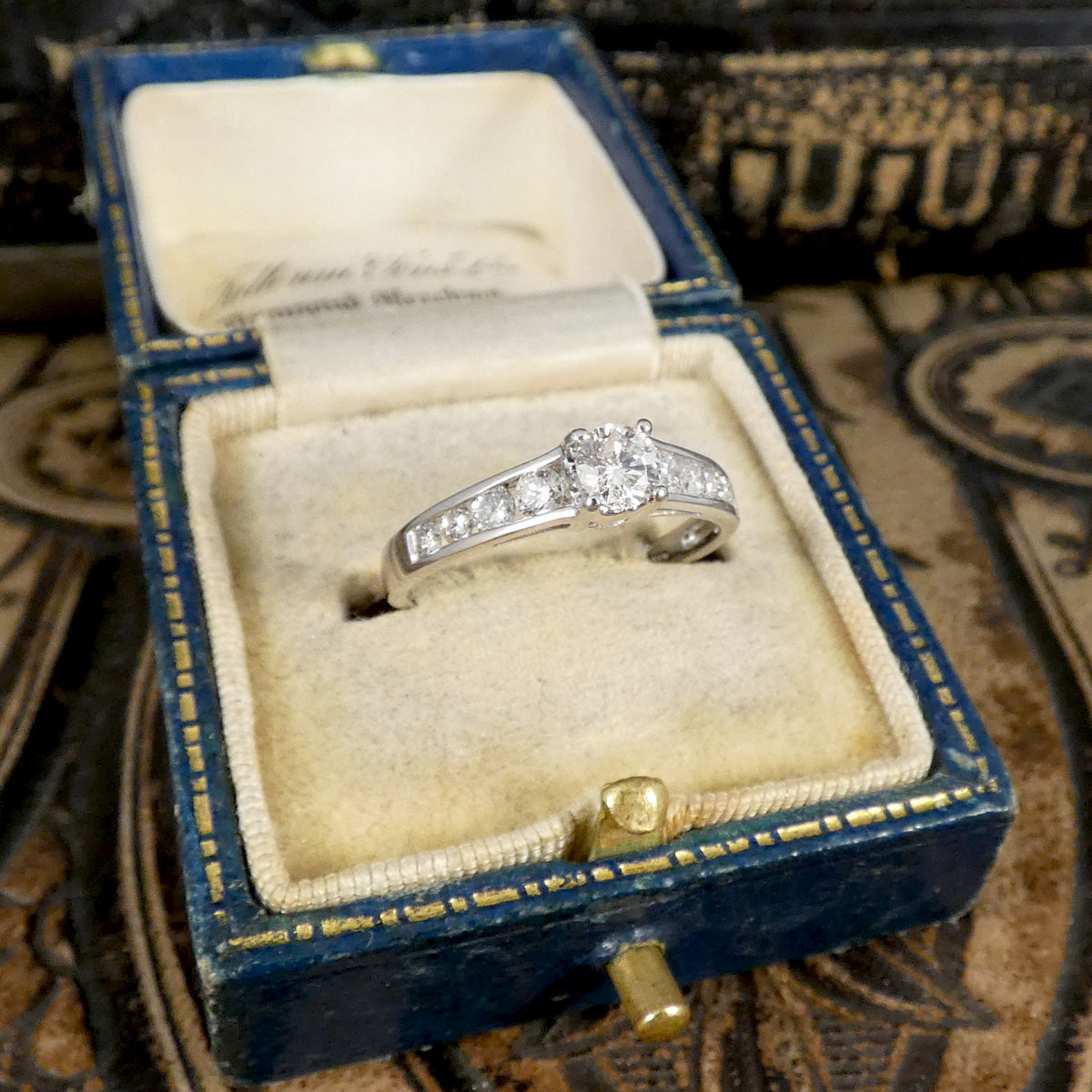 Diamond ring in an open jewelry box on a textured surface
