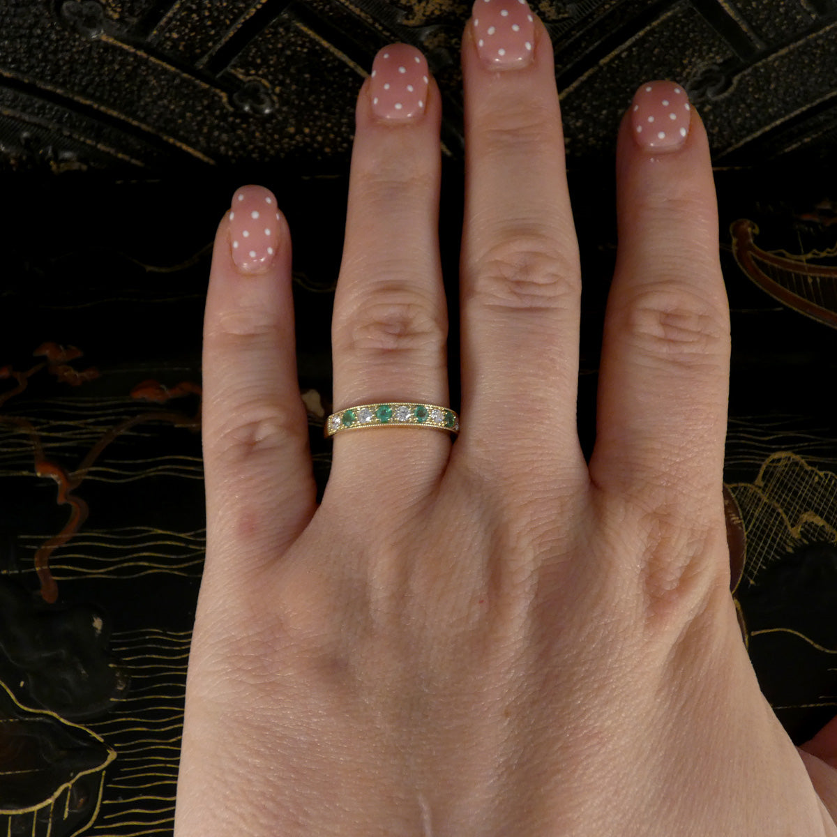 An Emerald and Diamond half eternity ring in yellow gold