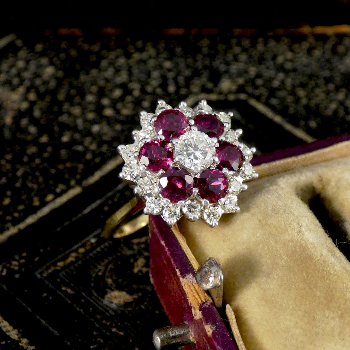 Elegant ring with red gemstones and diamonds on a textured surface