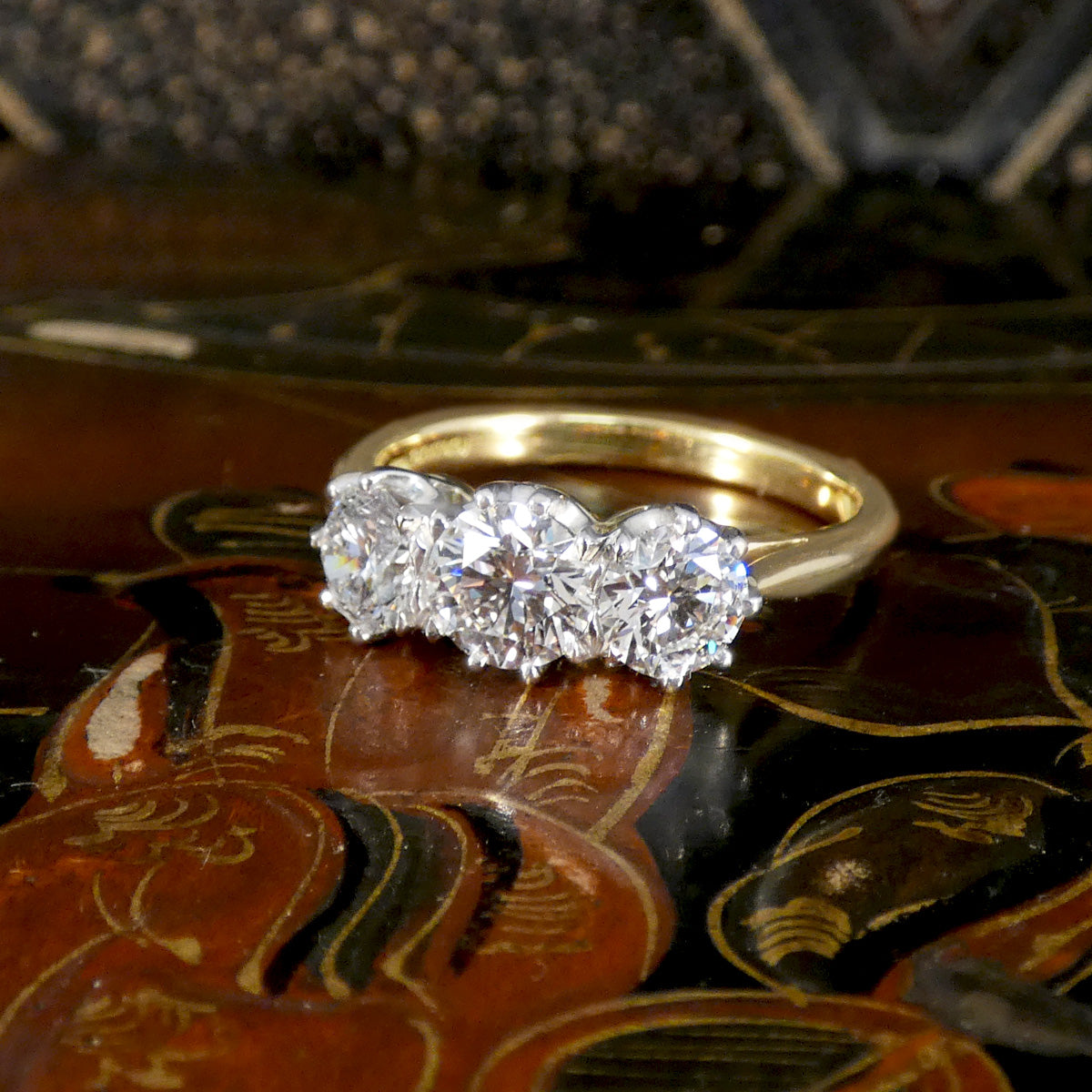 Gold ring with three diamonds on a decorative surface