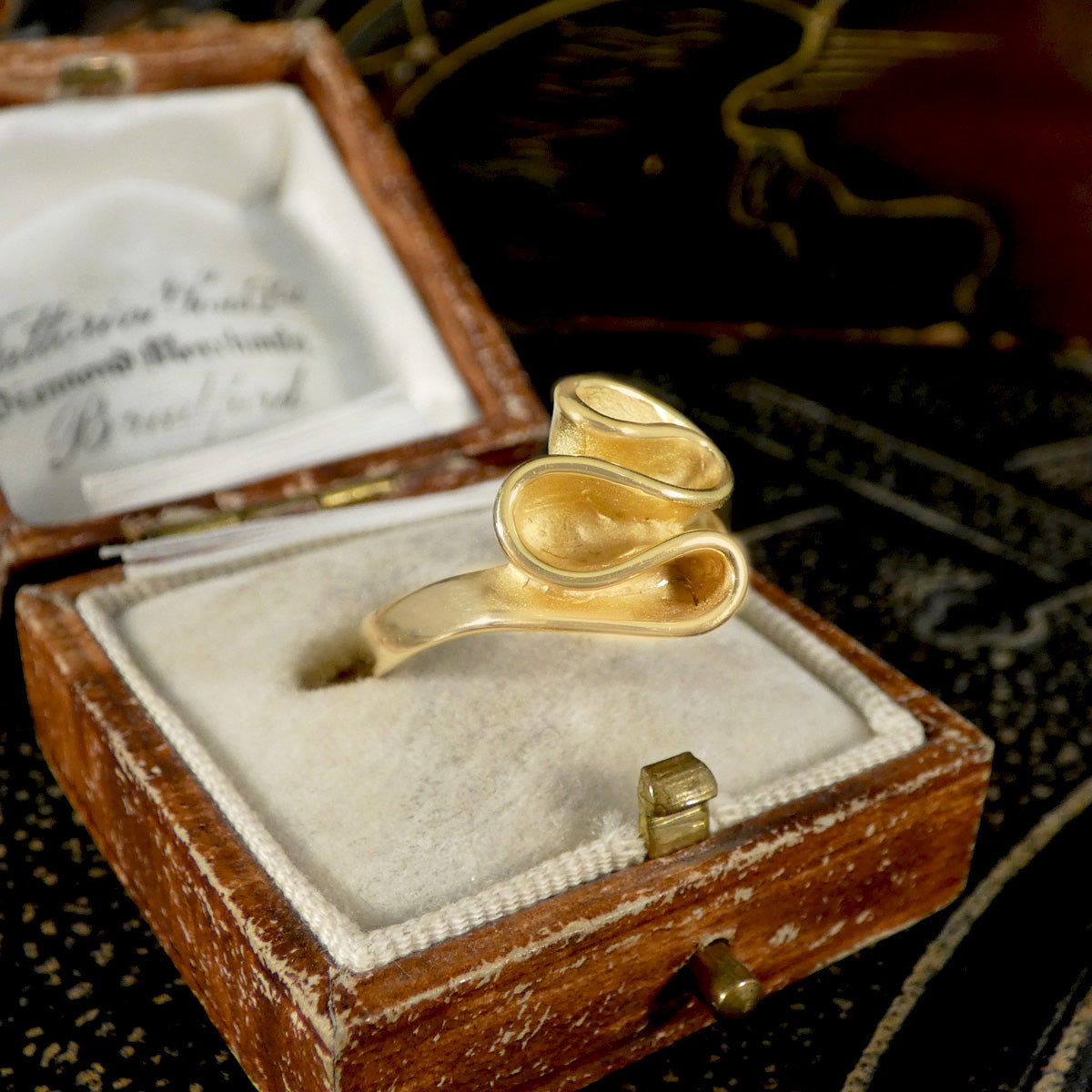 Gold ring in an open jewelry box with a blurred background