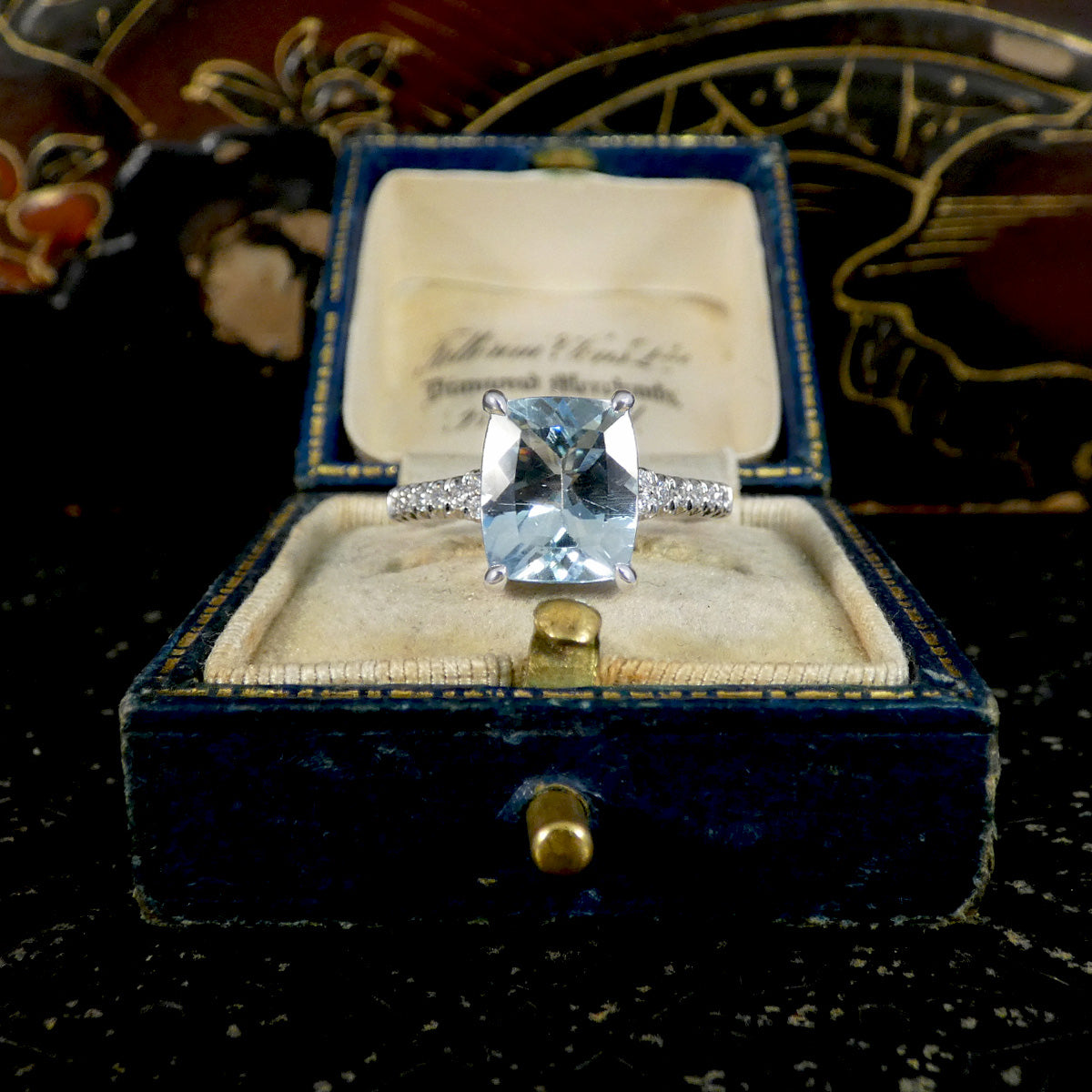 Diamond ring in a blue velvet box with a decorative background