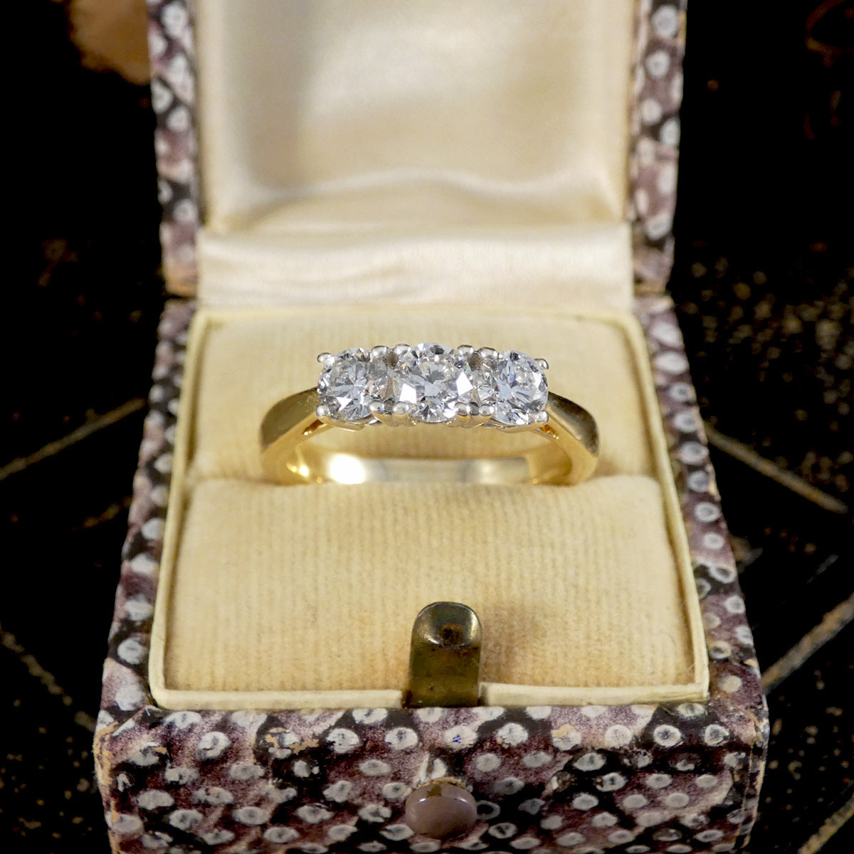 Gold ring with diamonds in a patterned jewelry box