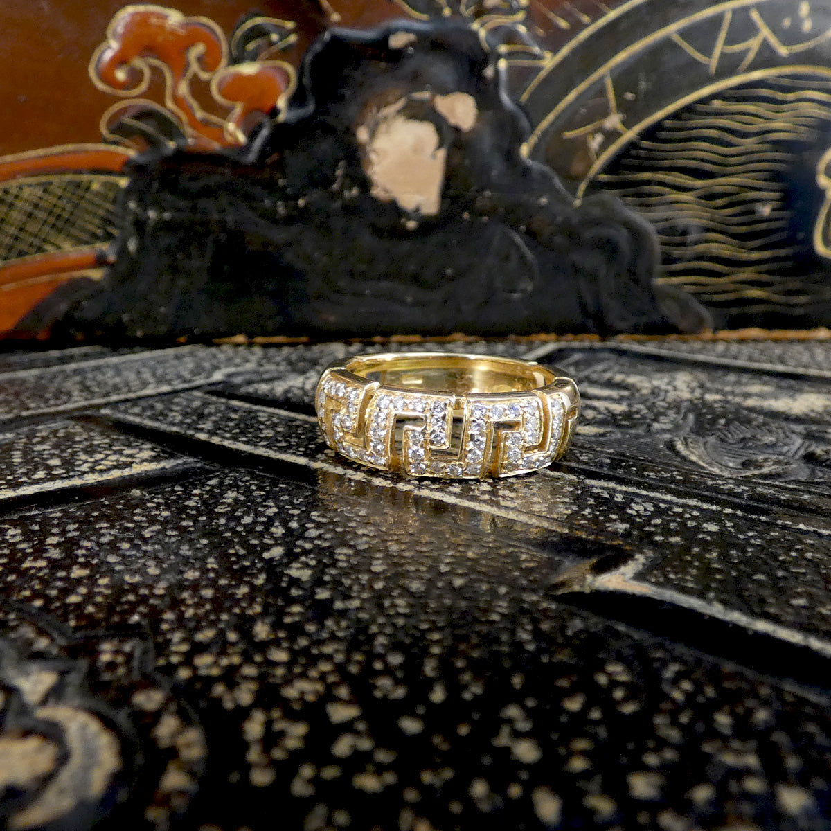 Gold ring with intricate design on a textured surface