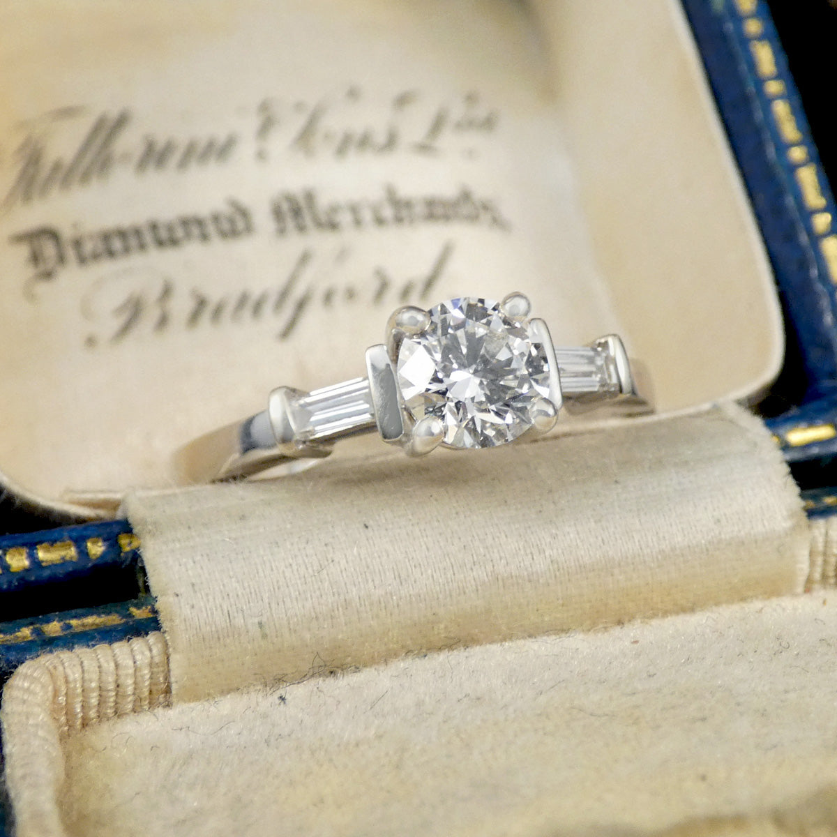 Diamond ring in an open jewelry box with visible text