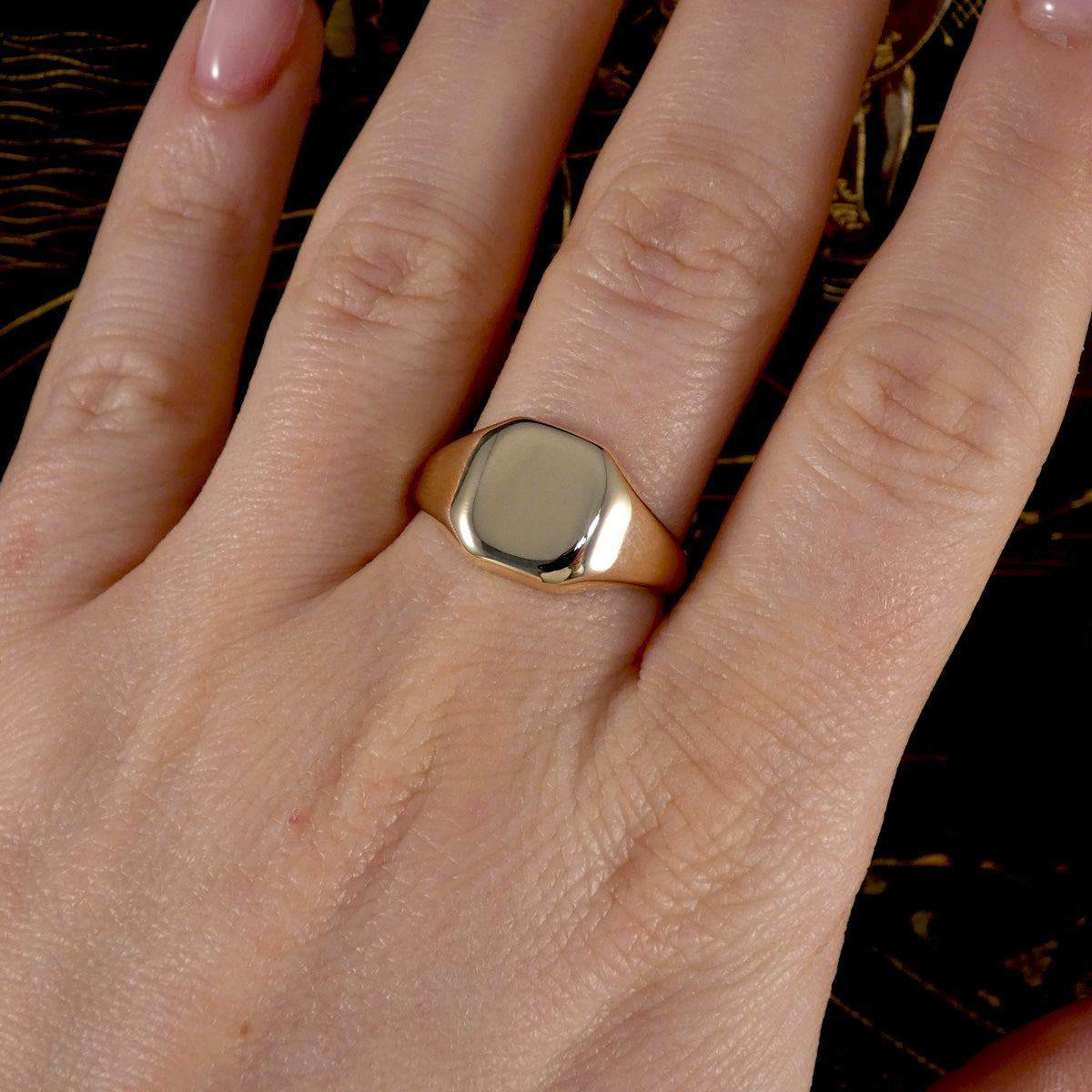 Gold ring on a person's finger with a dark background