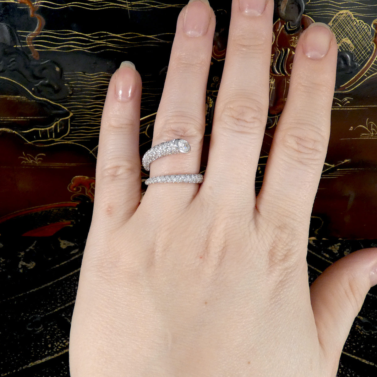 A unique diamond set snake like ring shown on the hand twisting round the finger.