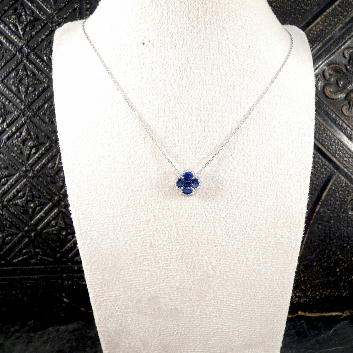 a blue sapphire shamrock necklace with a diamond surround on a burst