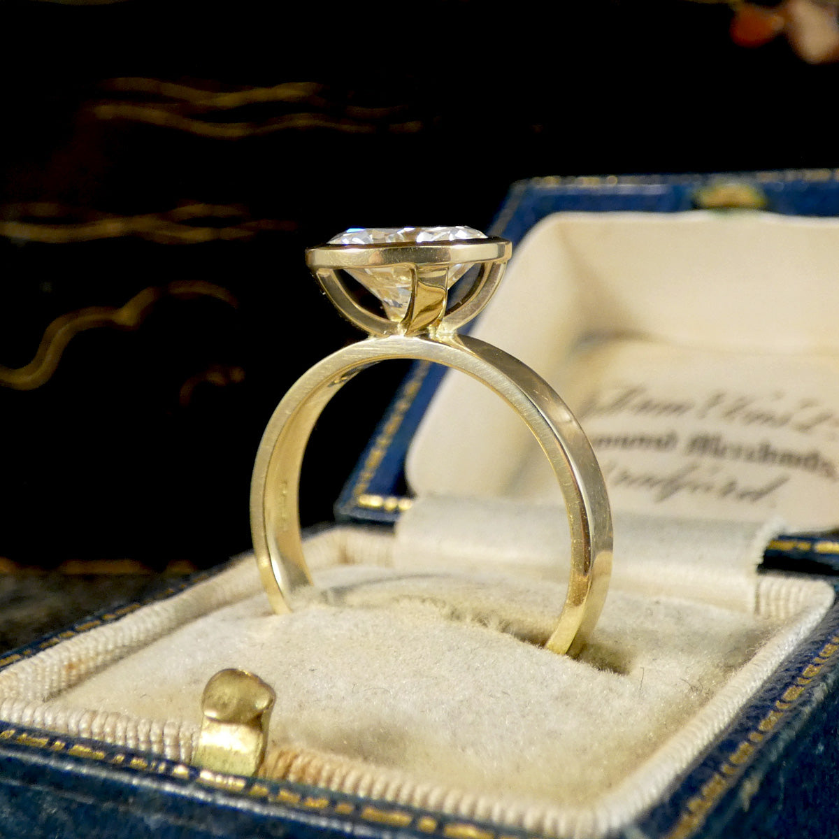 A diamond solitaire ring in a rub over bezel setting in 18ct yellow gold showing the gallery exposure 