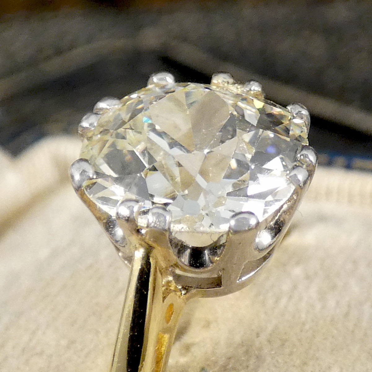 Close up of gold ring with a large diamond on a textured surface