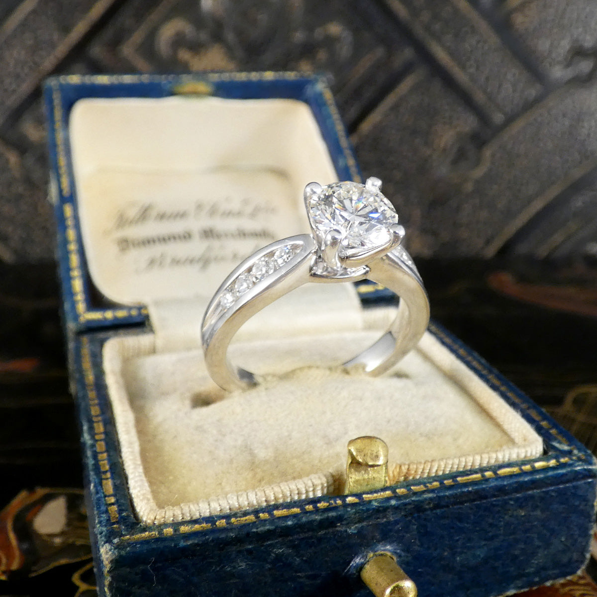 Diamond ring in an ornate blue jewelry box with gold accents