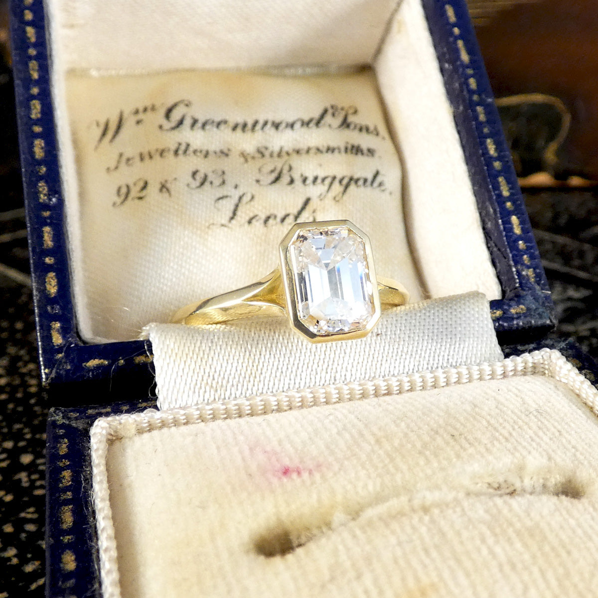 1.55ct Emerald Cut Diamond Solitaire in a Bezel Setting in 18ct Yellow Gold, showcasing a clear and bright diamond graded F/VS shown in vintage box.