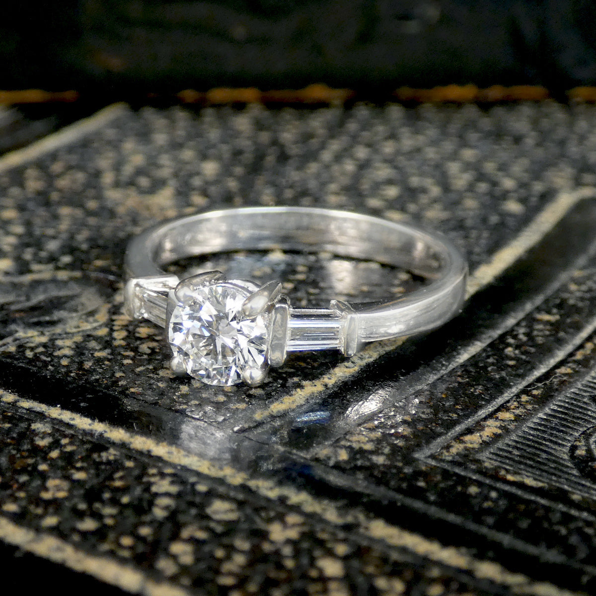 Silver ring with a diamond on an ornate surface