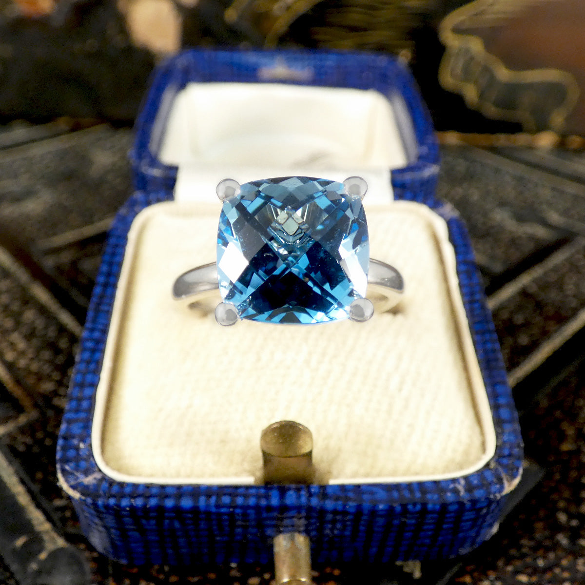 Blue gemstone ring in a blue box on a textured surface