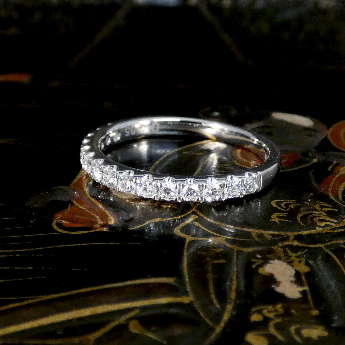 Platinum ring with diamonds on a reflective surface