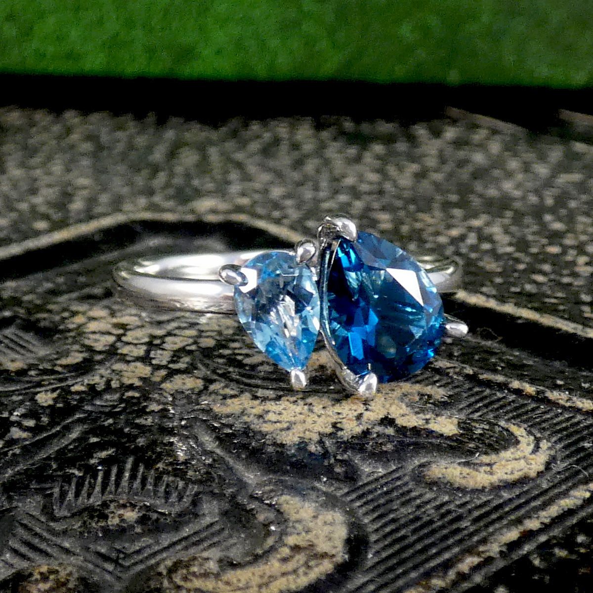 White Gold ring with blue topaz gemstones on a textured surface