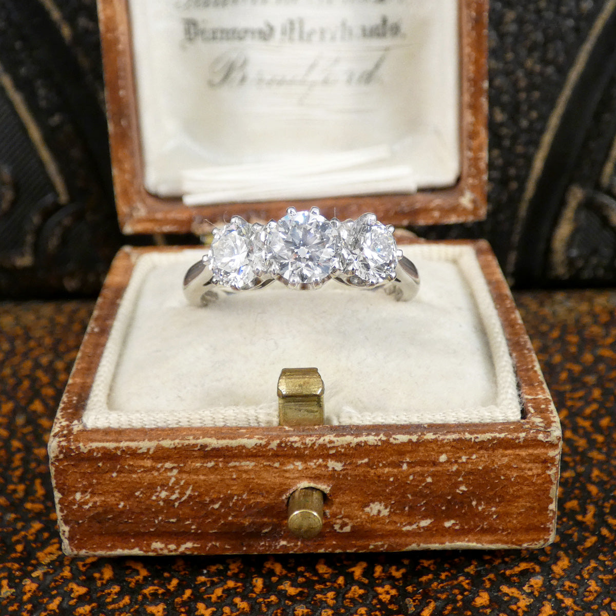 Diamond ring in a wooden box on an ornate surface