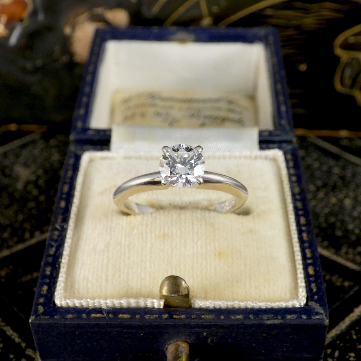 A diamond solitaire high set ring in white gold displayed on vintage box.