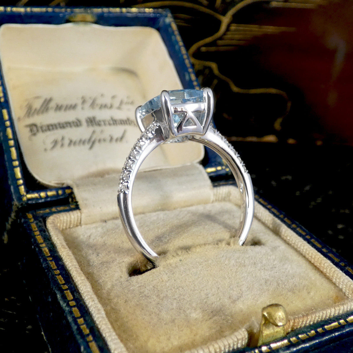 Diamond ring in an ornate blue and gold box with a visible brand name.