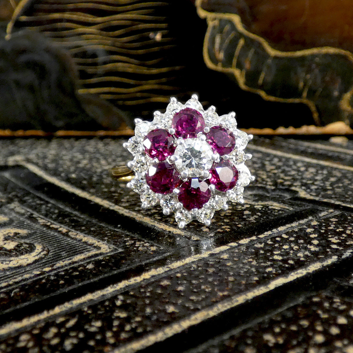 Ring with red gemstones and diamonds on a textured surface