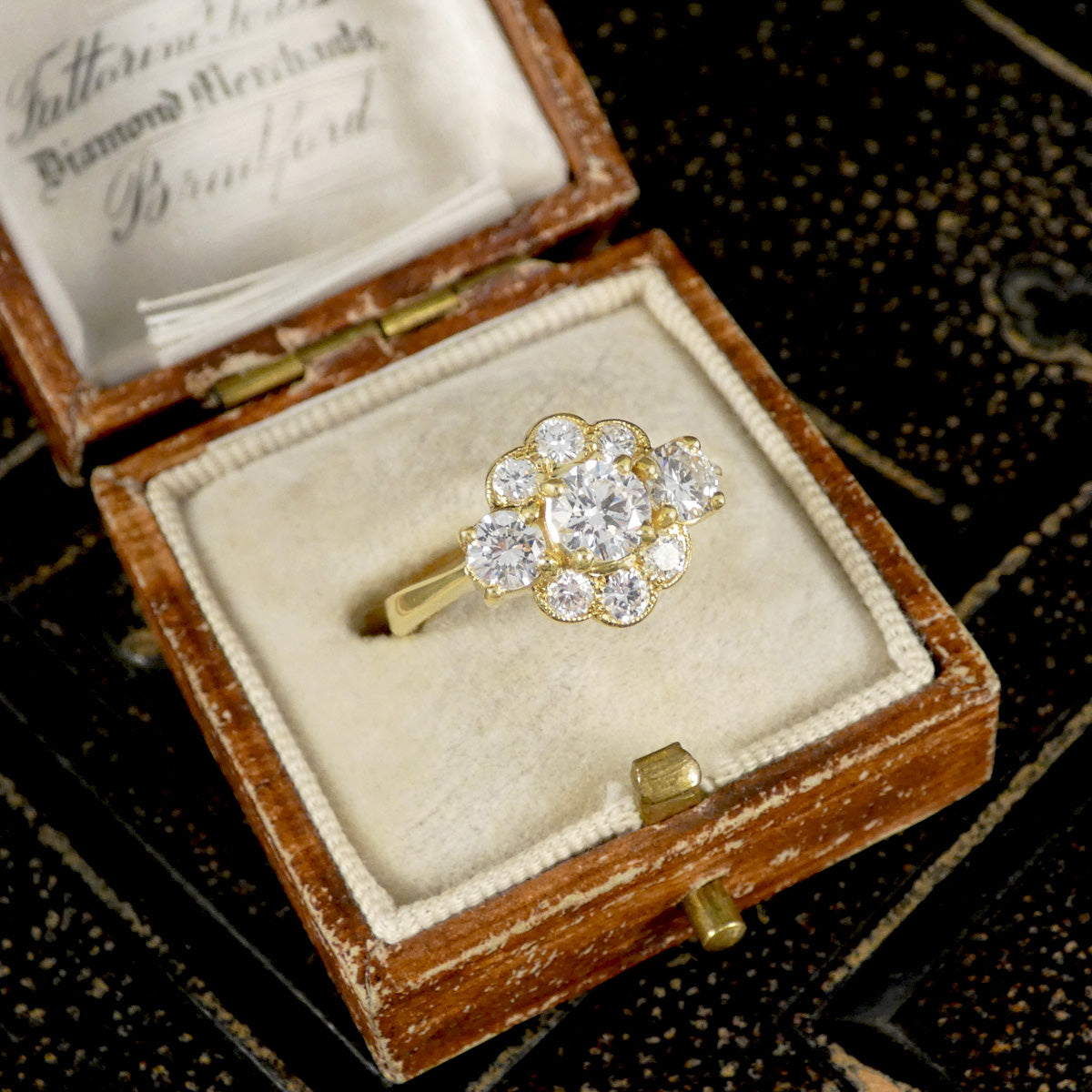 Gold ring with diamonds in an open jewelry box on a dark textured background