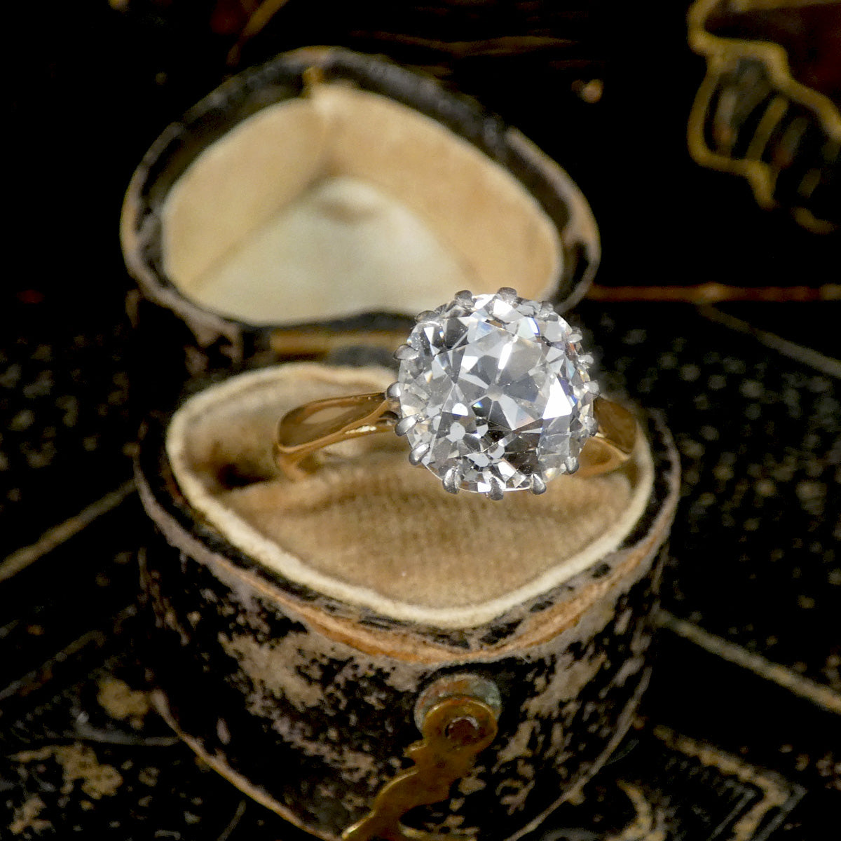 An Old Cushion shaped Mine cut diamond solitaire ring shown in an antique box.