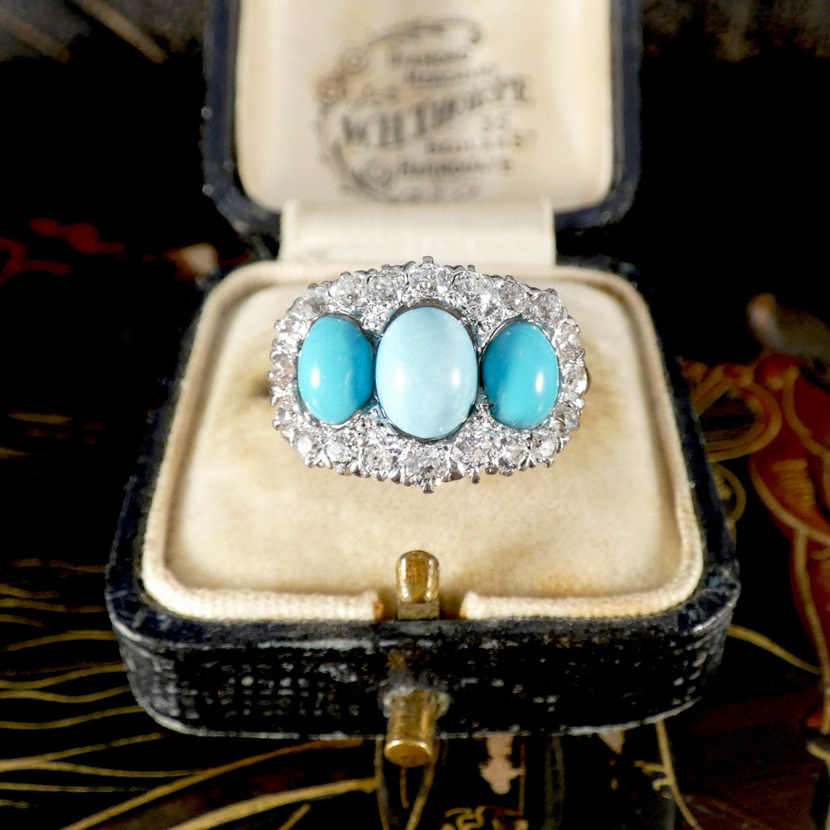 Turquoise ring with white gold setting in an open jewellery box on a patterned surface