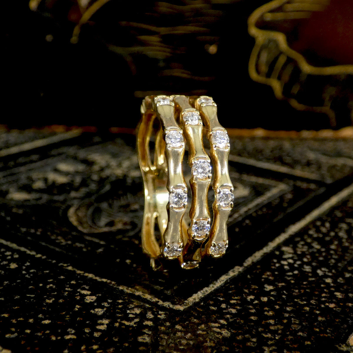Three strand bamboo style ring in yellow gold with diamonds shown on the side