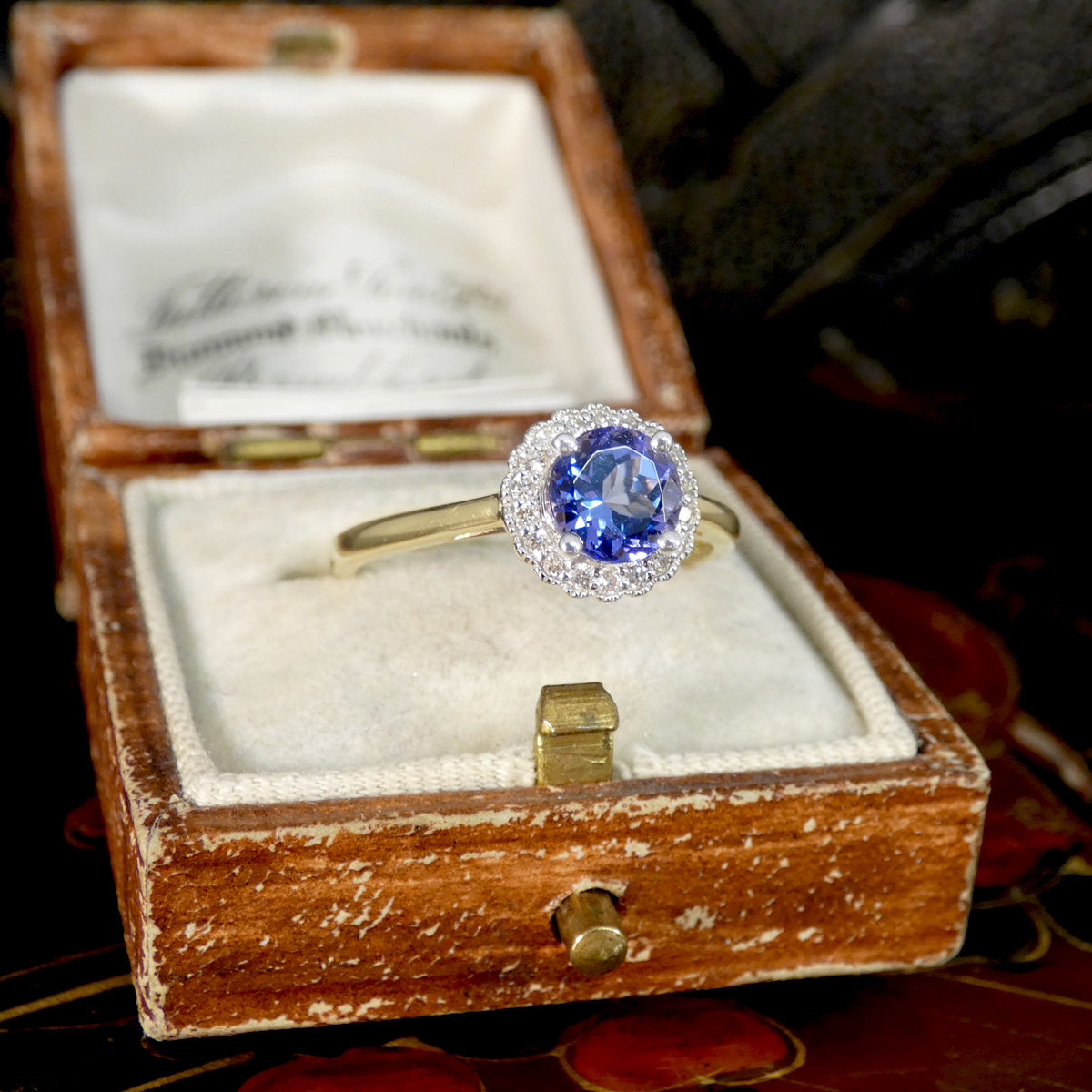 Gold ring with a blue gemstone in an open wooden box