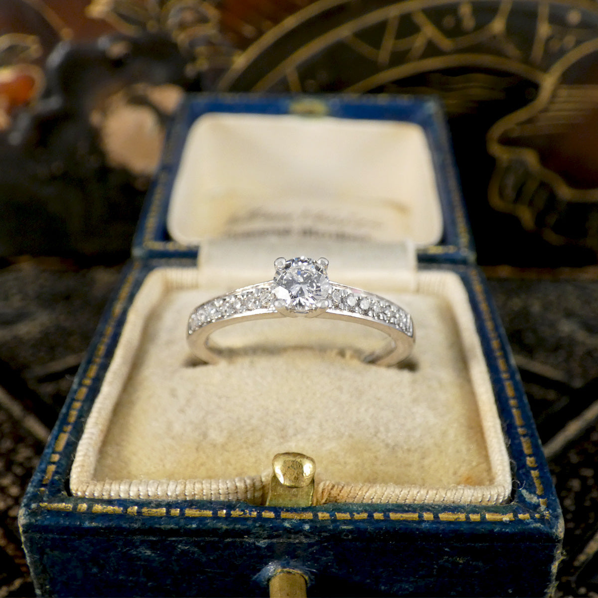 Diamond ring in a blue velvet box with intricate background