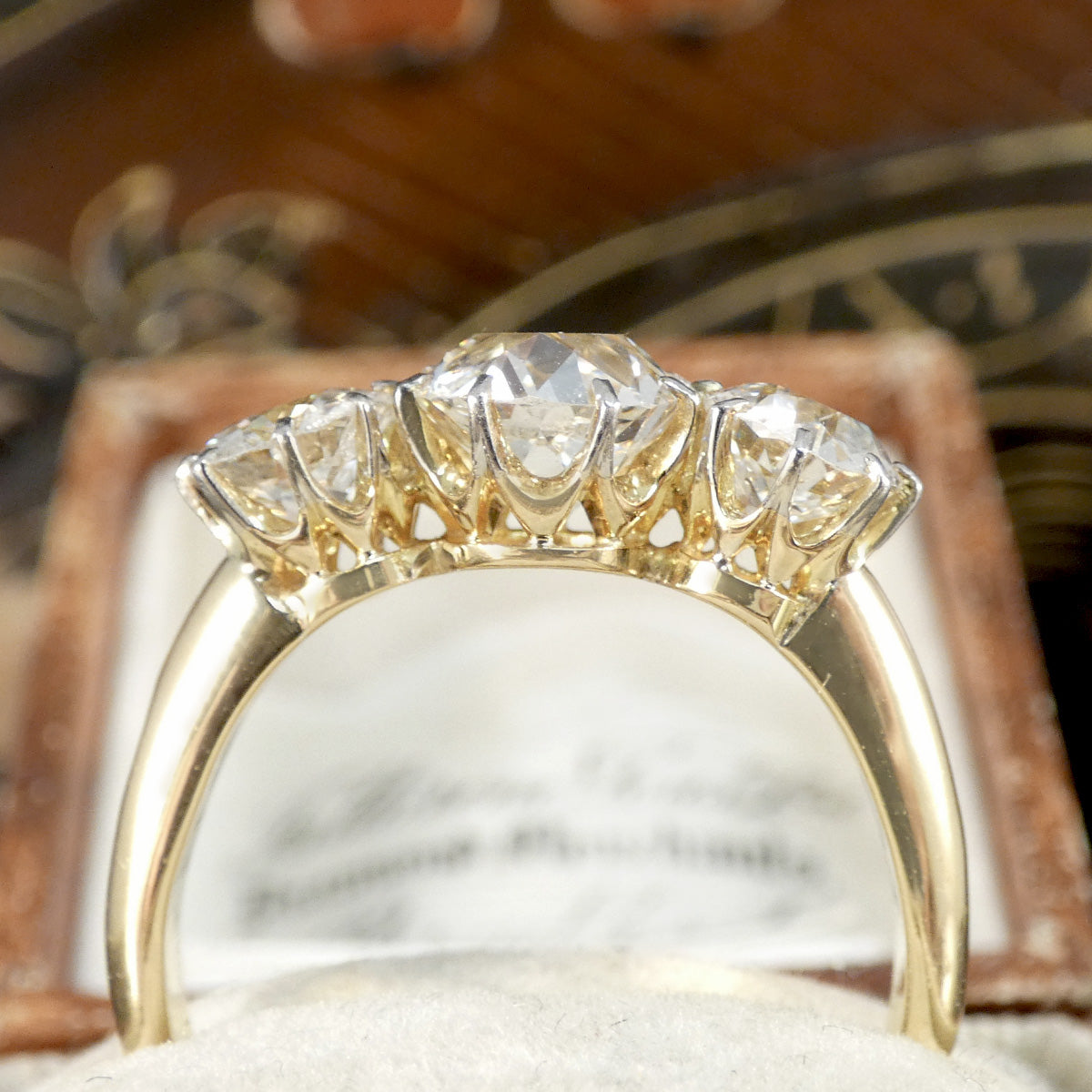 A chunky old cushion cut diamond three stone ring in 18ct yellow gold showing setting.