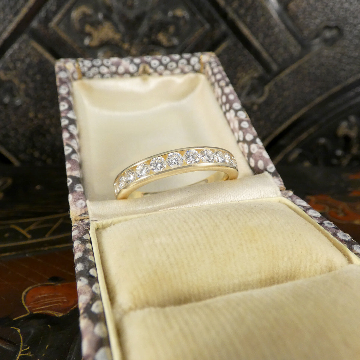 Gold ring with diamonds in a jewelry box on a decorative background