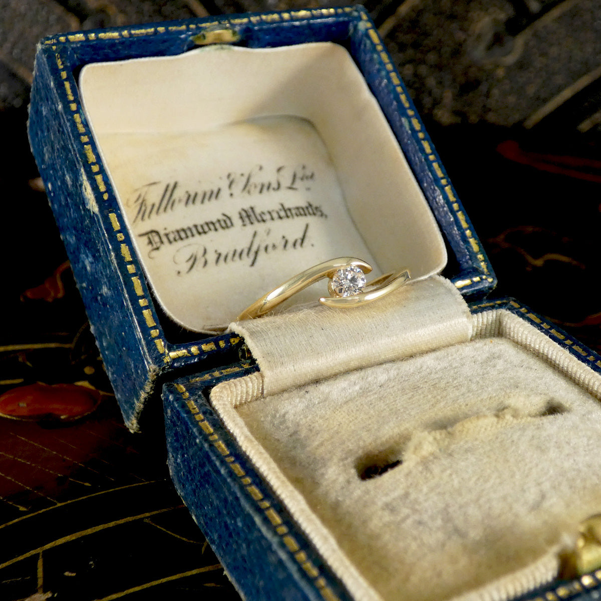Gold ring with diamond in an open jewellery box.