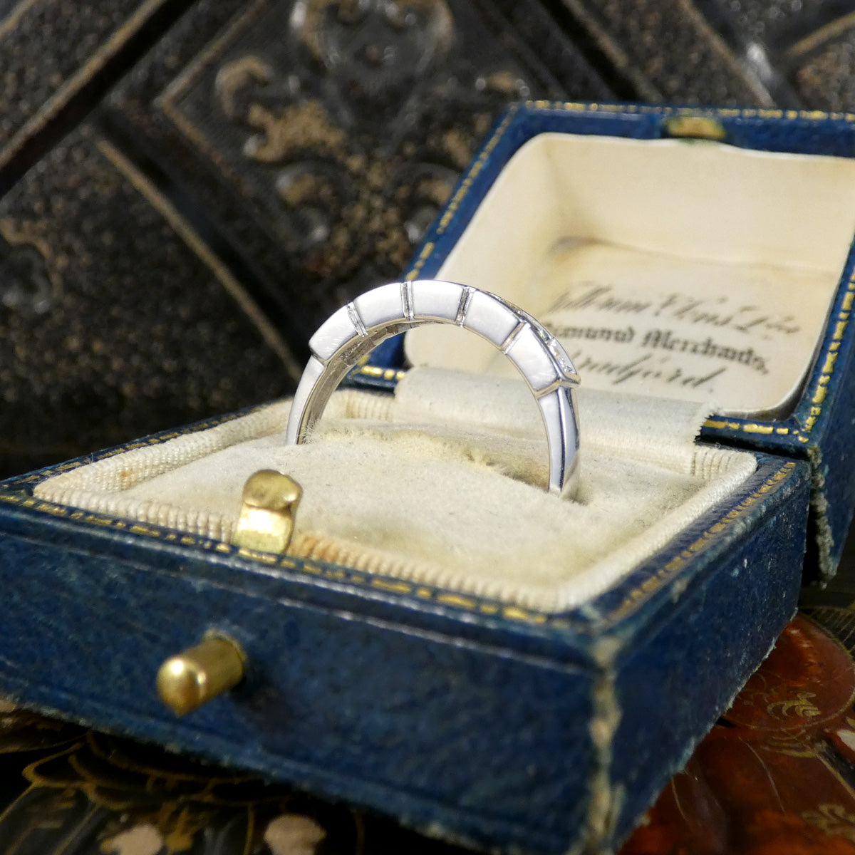 Silver ring in a blue jewelry box with an old document inside
