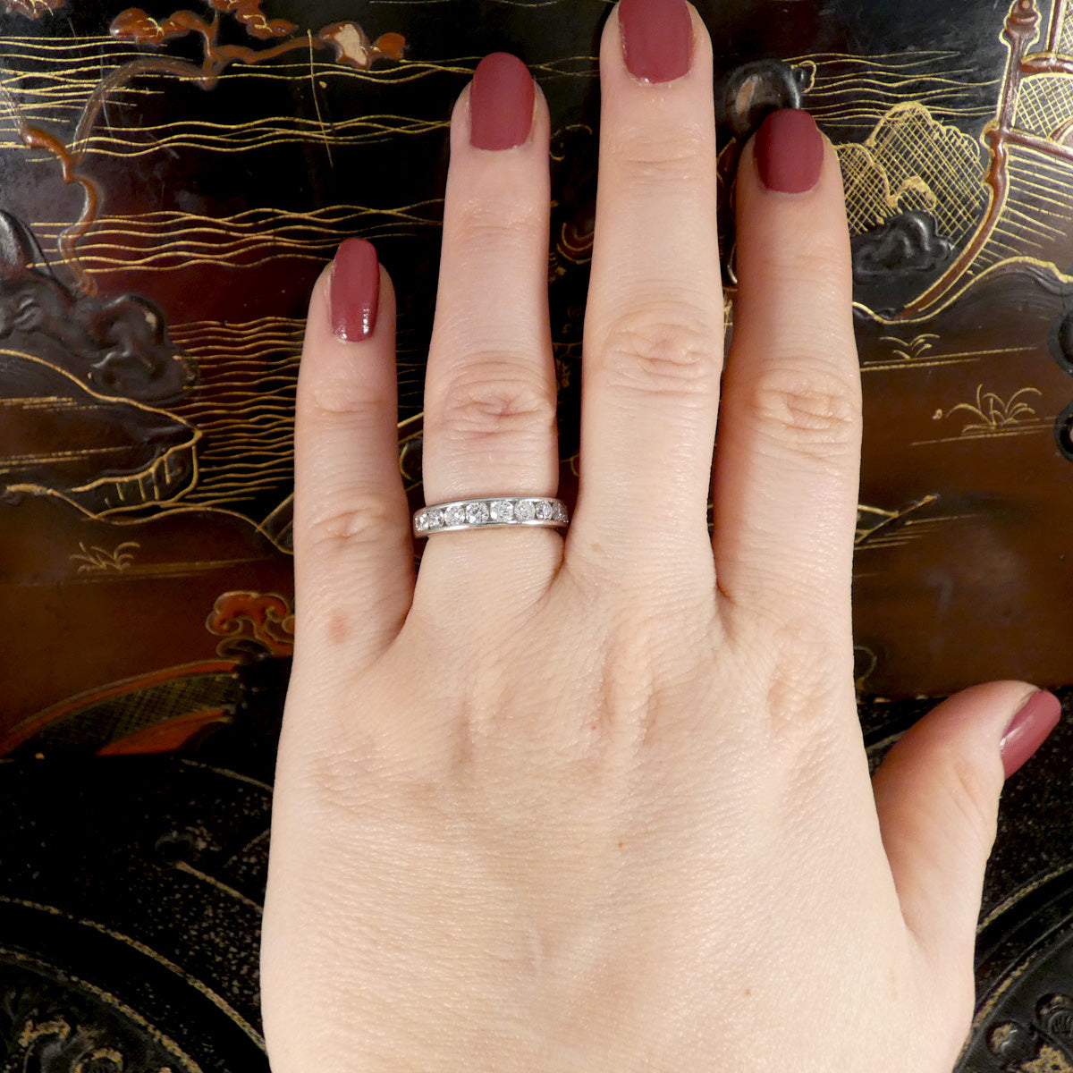 A diamond channel set ring in platinum shown on the hand.