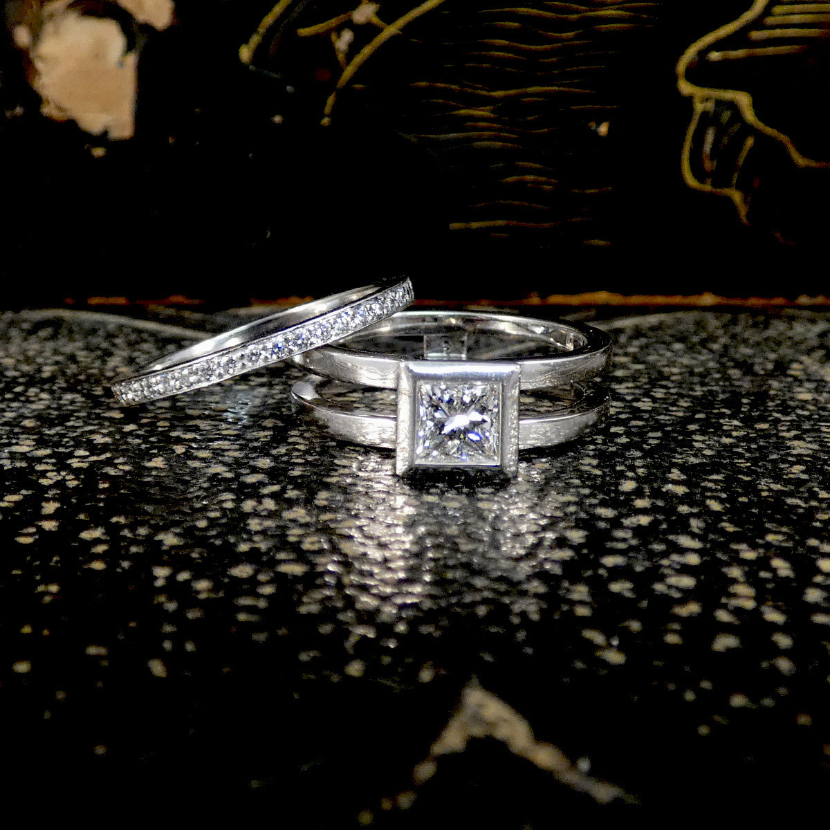 Two Platinum rings with diamond accents on a textured surface