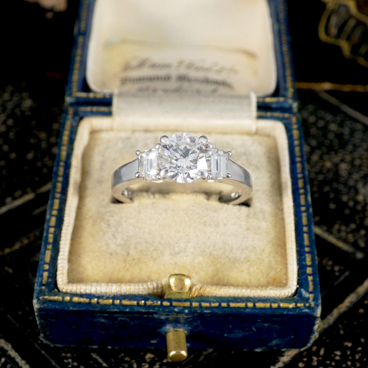 A brilliant cut and trapezoid cut Diamond three stone ring in jewellery box.