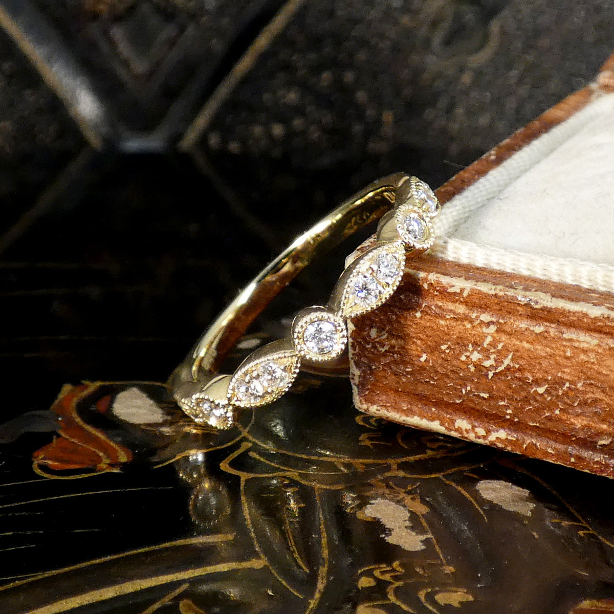 Gold ring with diamonds on a decorative surface