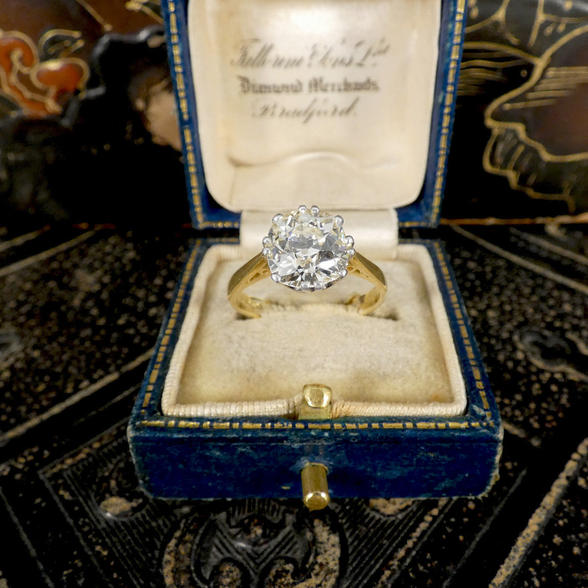 Gold ring with a diamond in an open blue velvet box on a decorative background