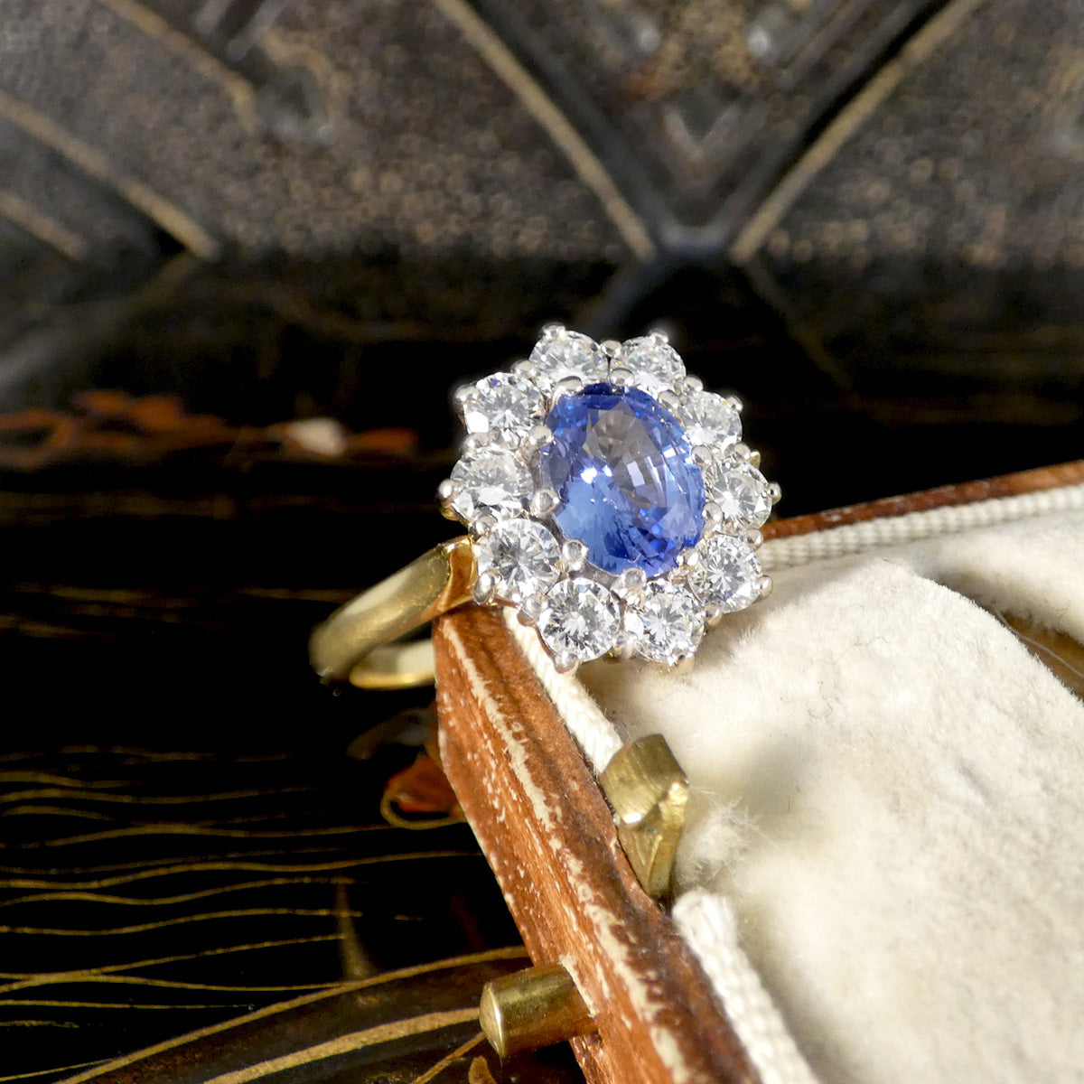 Gold ring with a blue sapphire gemstone and diamond accents on a textured surface