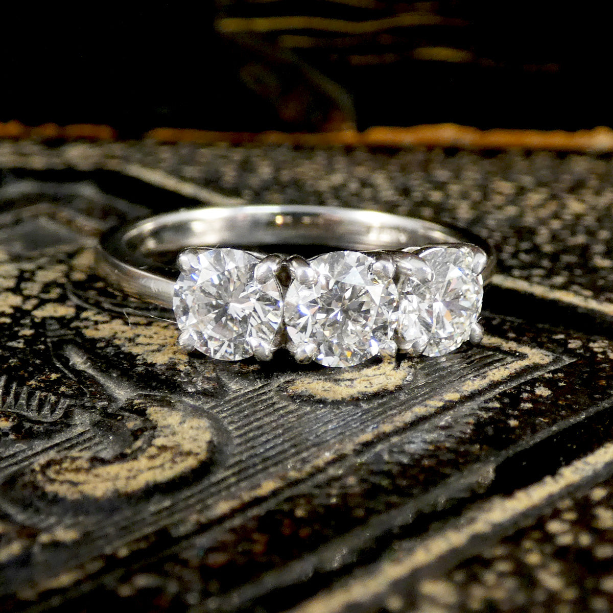 Platinum ring with three diamonds on a textured surface