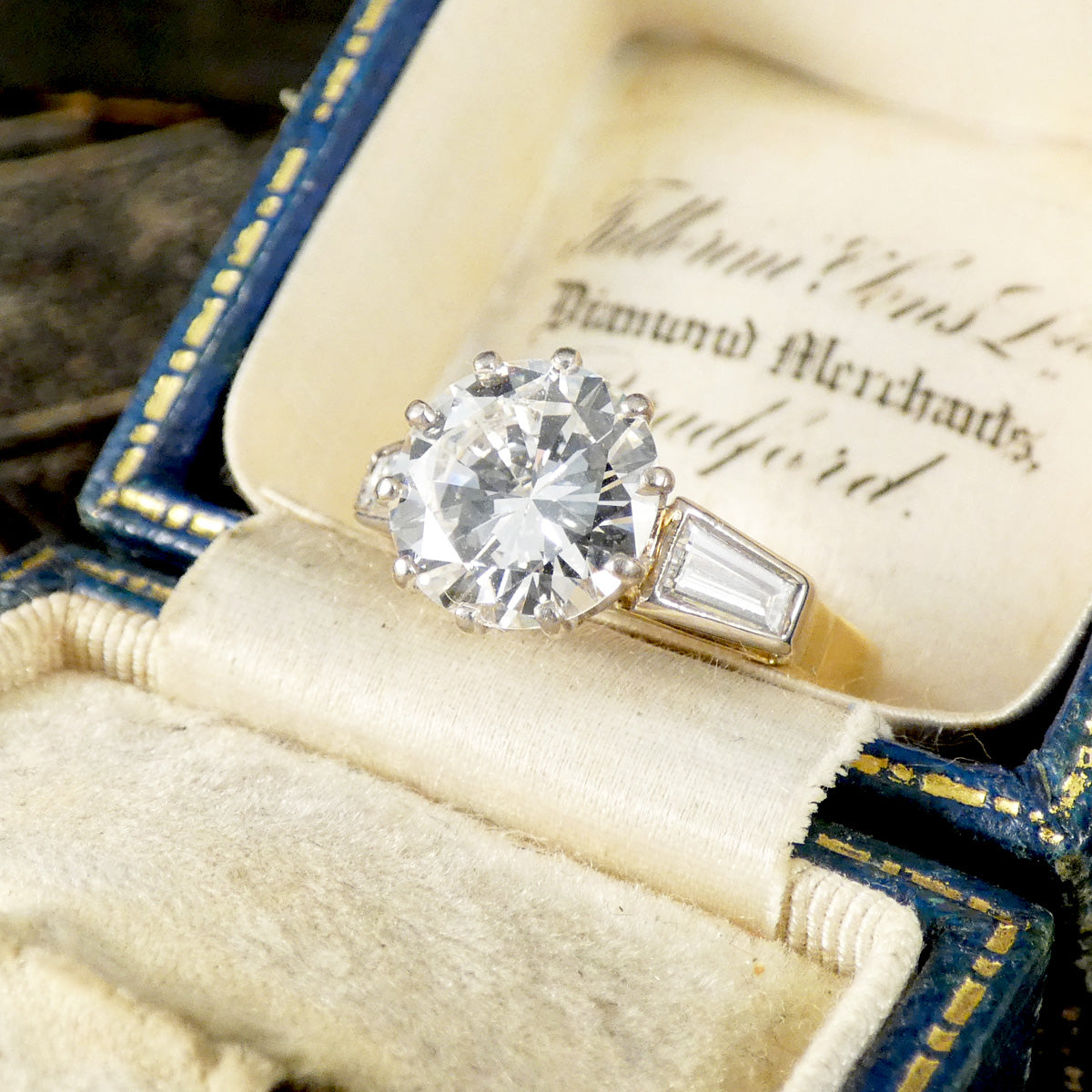 Diamond engagement ring in an open jewelry box with visible text
