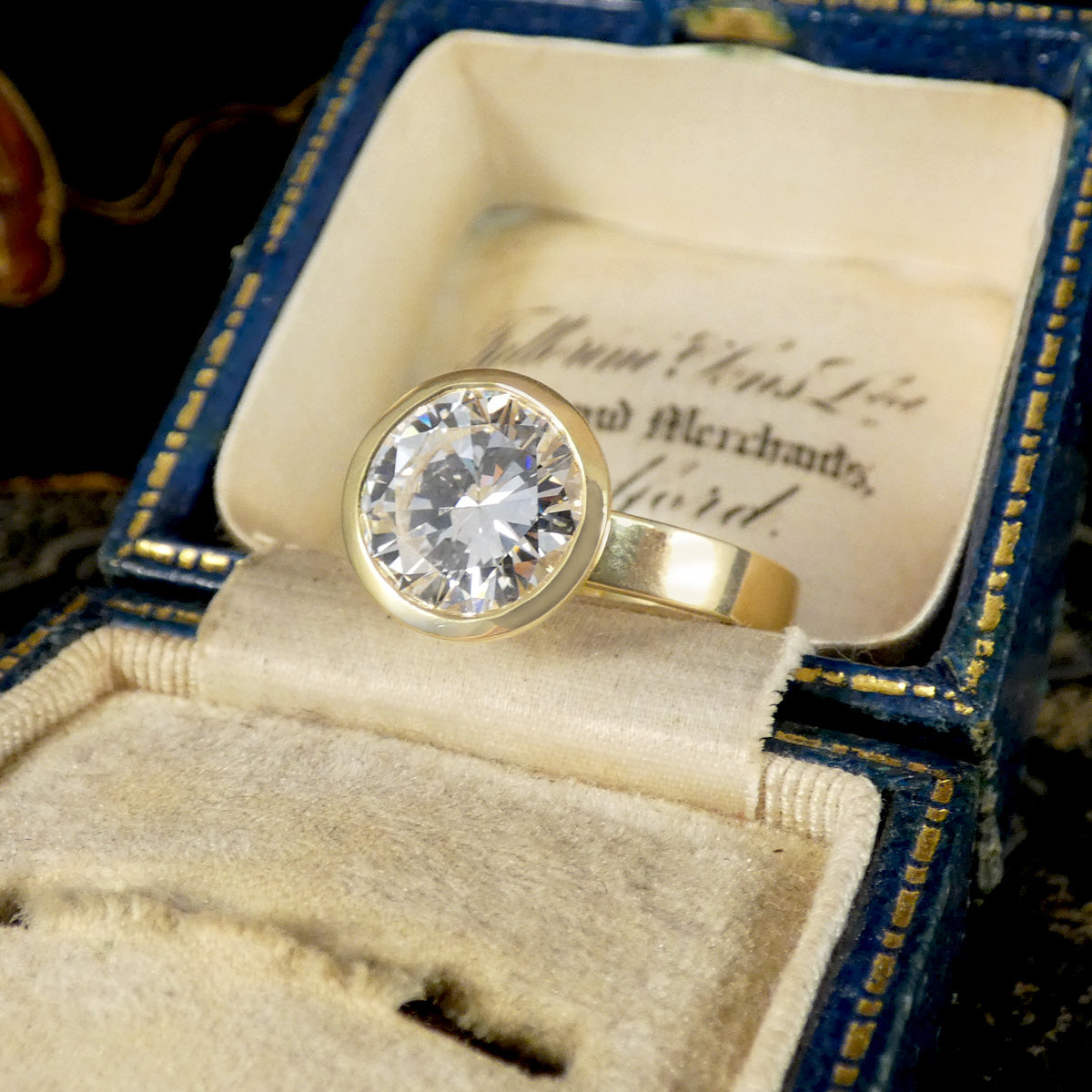 A diamond solitaire ring in a rub over bezel setting in 18ct yellow gold shown in vintage box