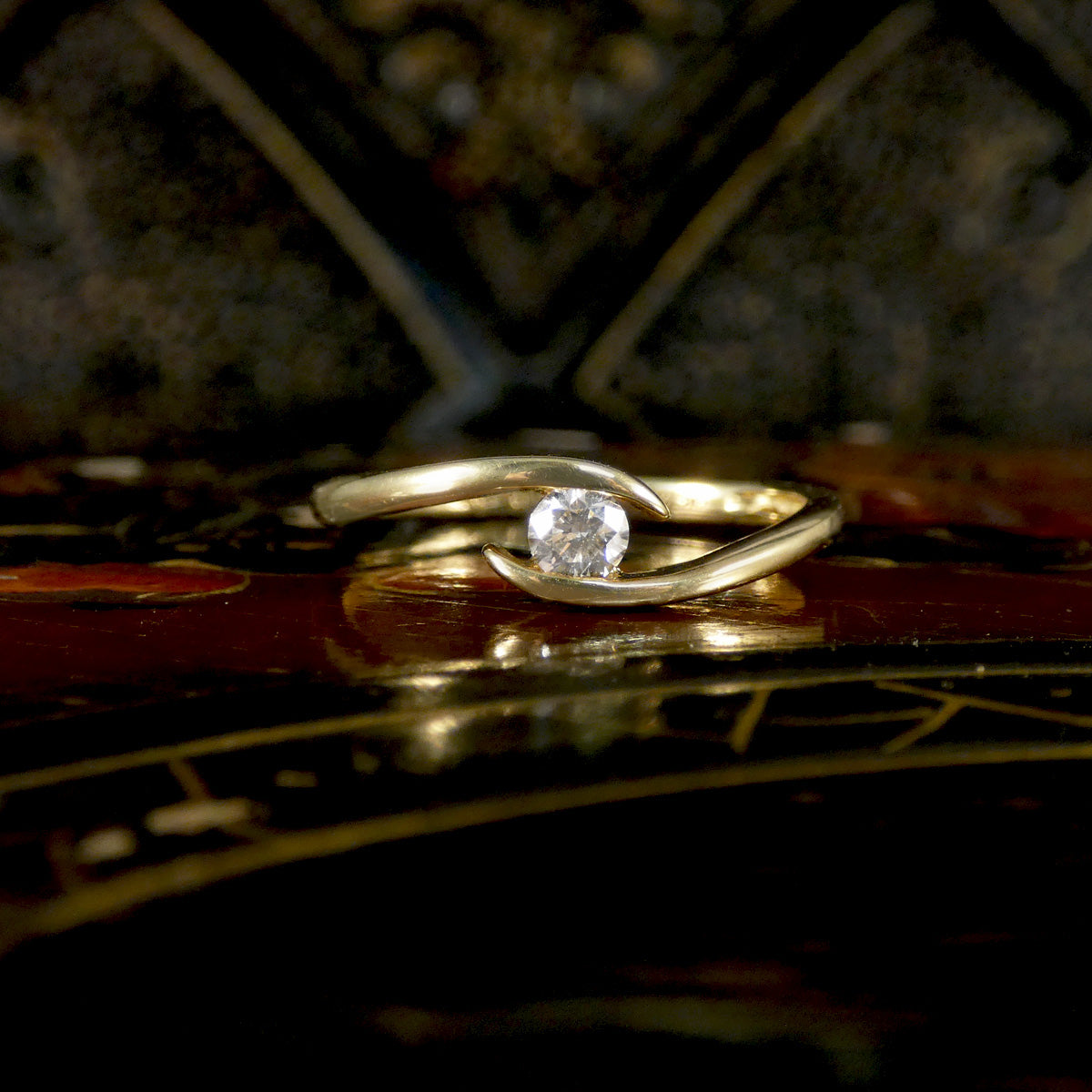 Gold ring with a diamond on an ornate surface